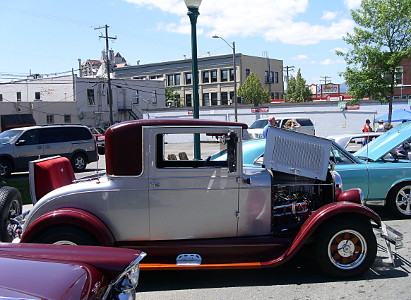 [This parked car is silver and red and has the seat opened and the hood partially open.]